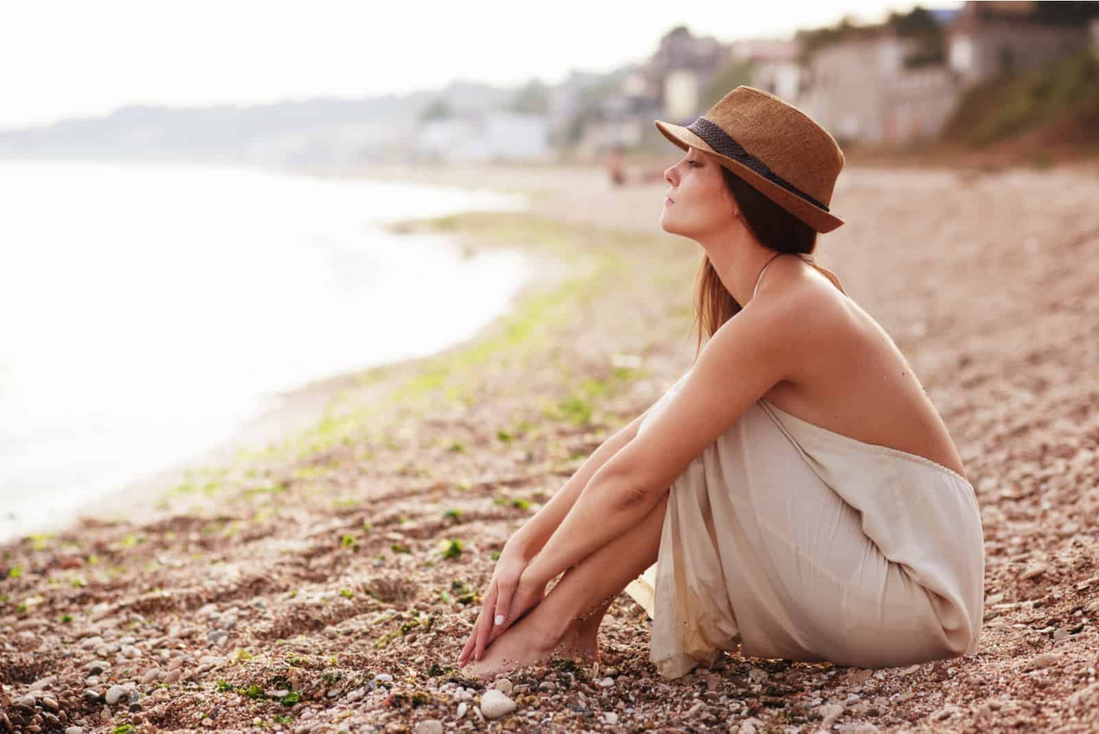 une femme imaginaire avec un chapeau sur la tête est assise sur la plage